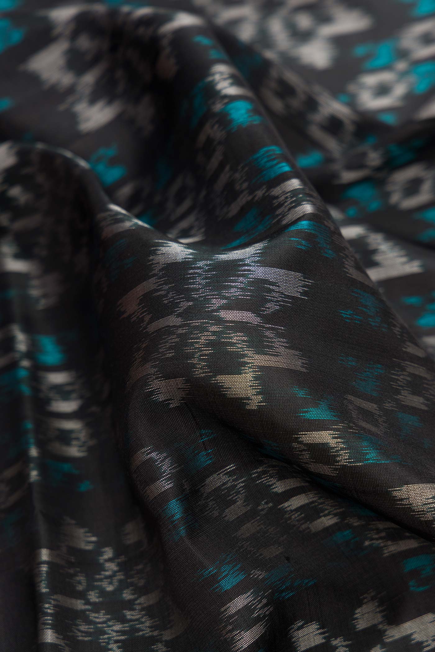 Close up of Black Dual Tone Soft Silk Saree with Ikat Print on the body and Zari Border.  displaying folds