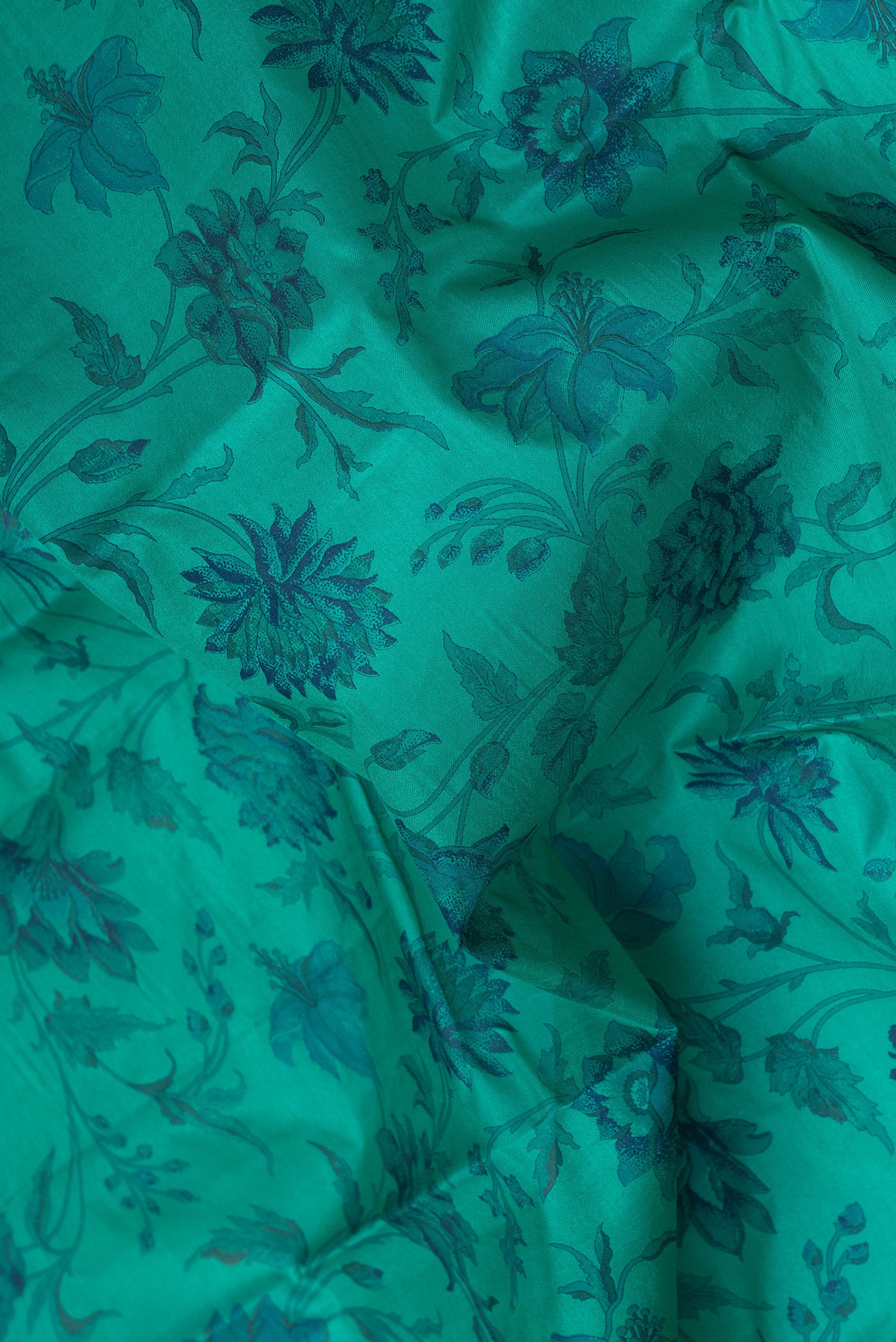 Close up of Teal Printed Silk Saree with Printed design on the body and Zari Border.  displaying folds