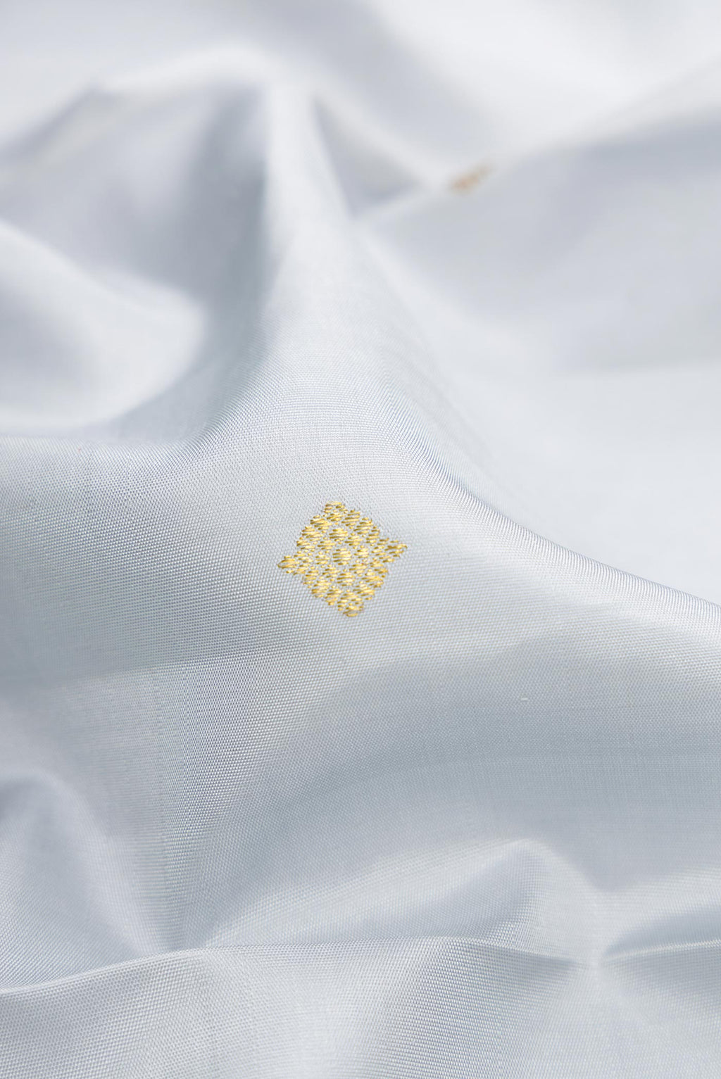 Close up of Grey Dual Tone Kanjivaram Silk Saree with Zari Butta on the body and Zari Border.  displaying folds