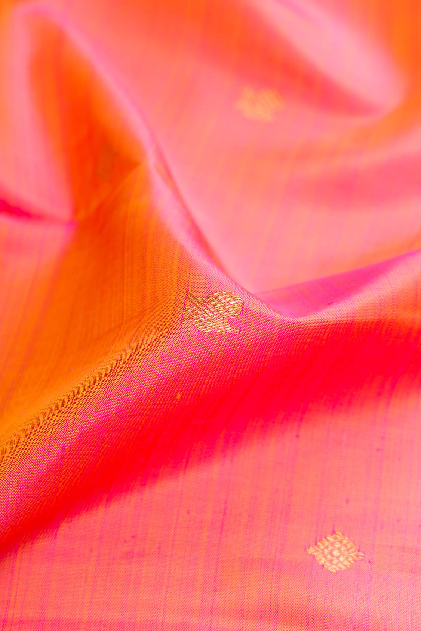Close up of Orange Dual Tone Kanjivaram Silk Saree with Zari Butta on the body and Zari Border.  displaying folds