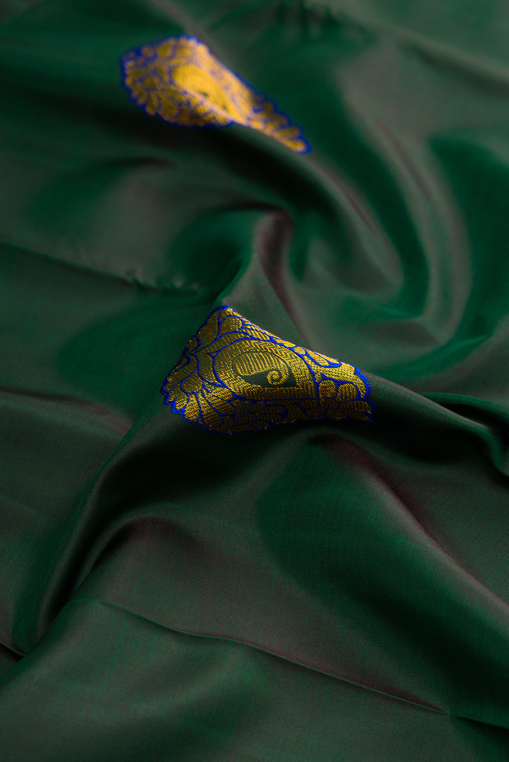 Close up of Green Dual Tone Kanchipuram Silk Saree with Zari And Thread Butta on the body and Zari Border.  displaying folds