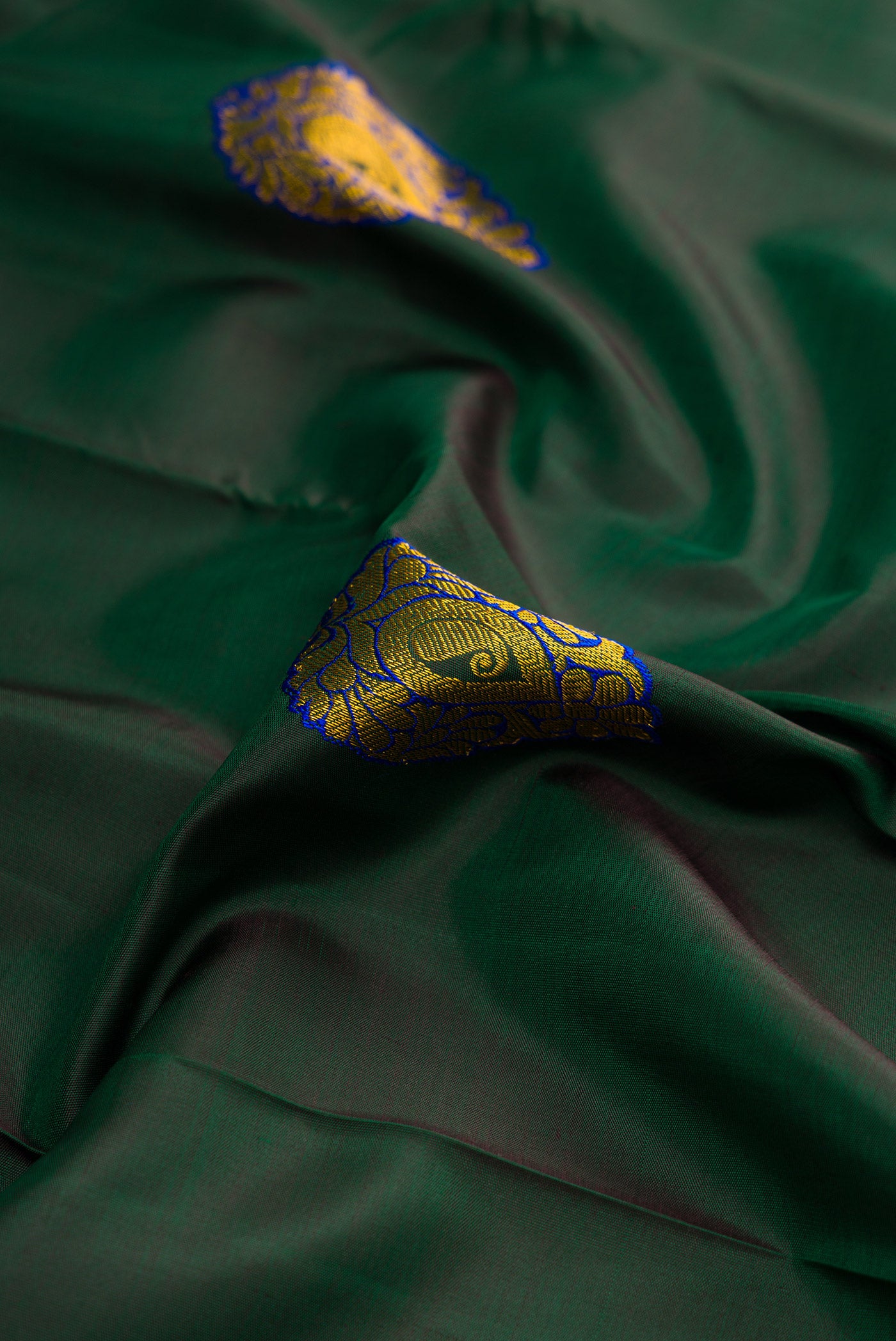 Close up of Green Dual Tone Kanchipuram Silk Saree with Zari And Thread Butta on the body and Zari Border.  displaying folds