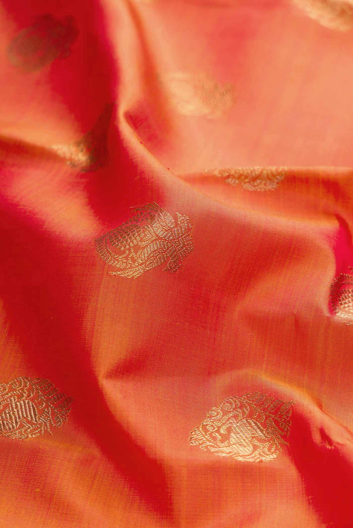 Close up of Pure Silk Pure Zari Orange Dual Tone Kanchipuram Saree with Zari Butta on the body and Zari Border displaying folds
