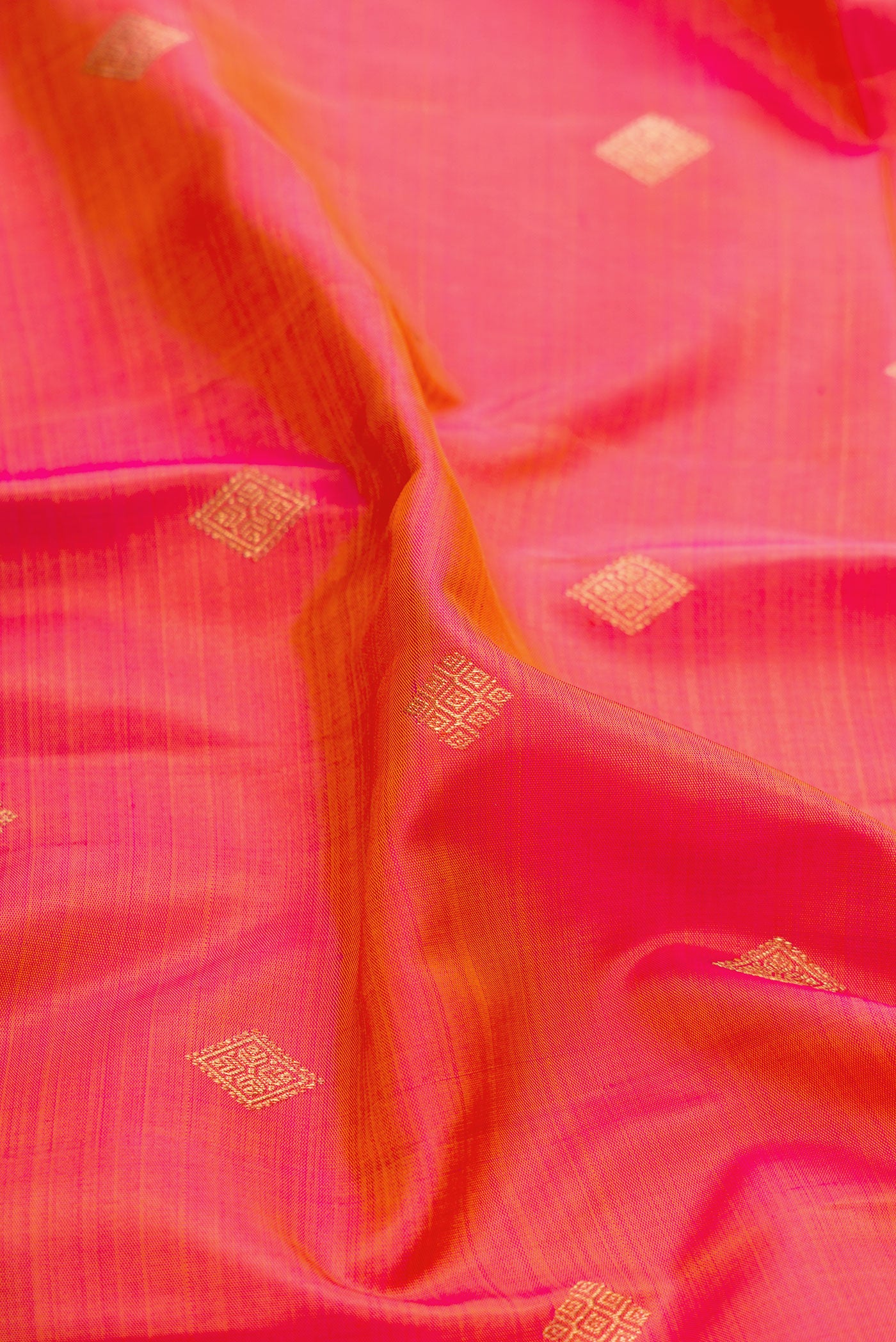 Close up of Pure Silk Pure Zari Rose Gold Dual Tone Kanchipuram Saree with Zari Butta on the body and Zari And Thread Border.  displaying folds