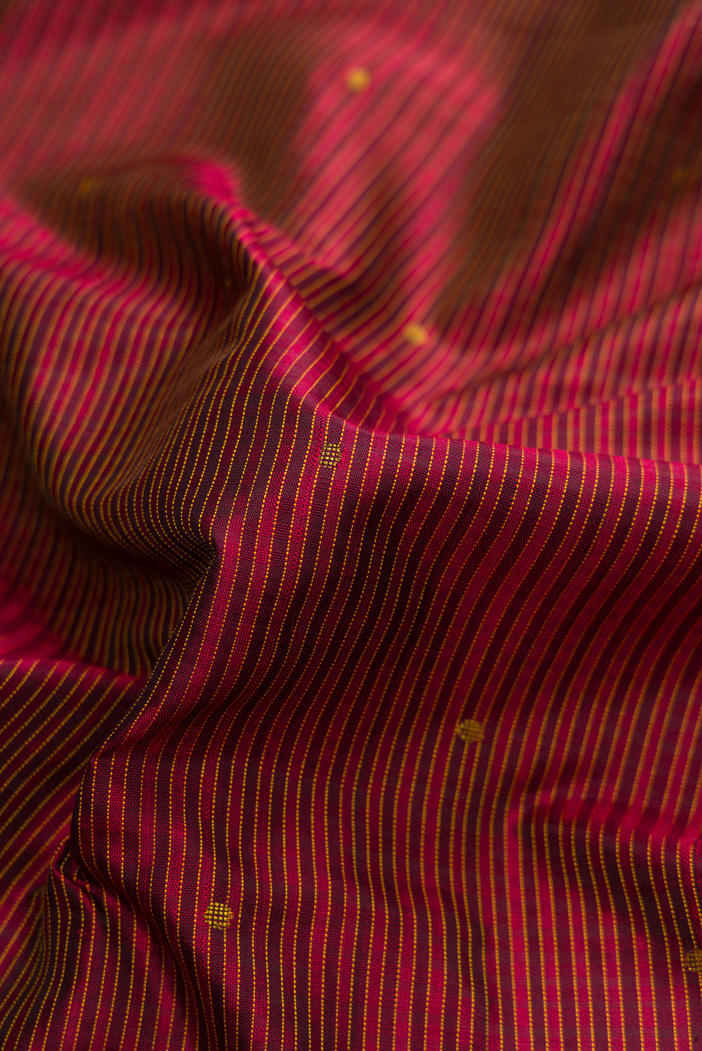 Close up of Pure Silk Pure Zari Maroon Dual Tone Kanchipuram Saree with Zari And Thread Butta on the body and Thread Border.  displaying folds