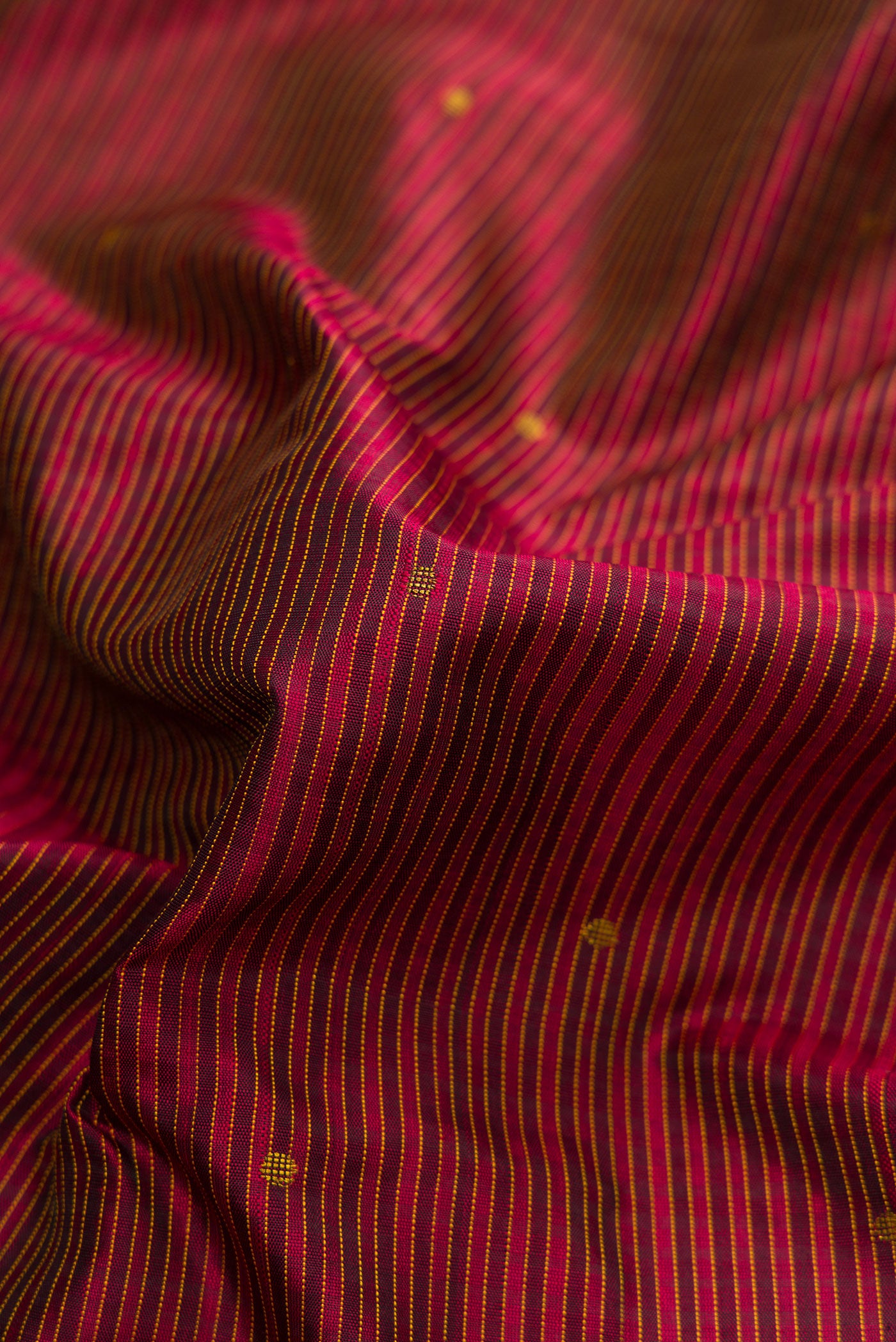 Close up of Pure Silk Pure Zari Maroon Dual Tone Kanchipuram Saree with Zari And Thread Butta on the body and Thread Border.  displaying folds