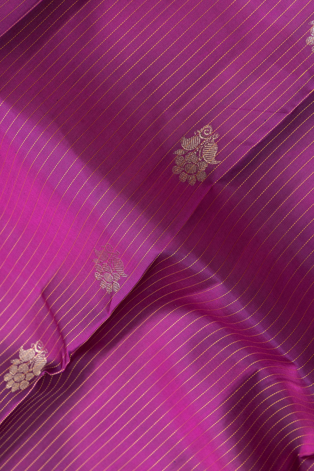 Close up of Magenta Dual Tone Kanjivaram Silk Saree with Stripes on the body and Zari Border.  displaying folds