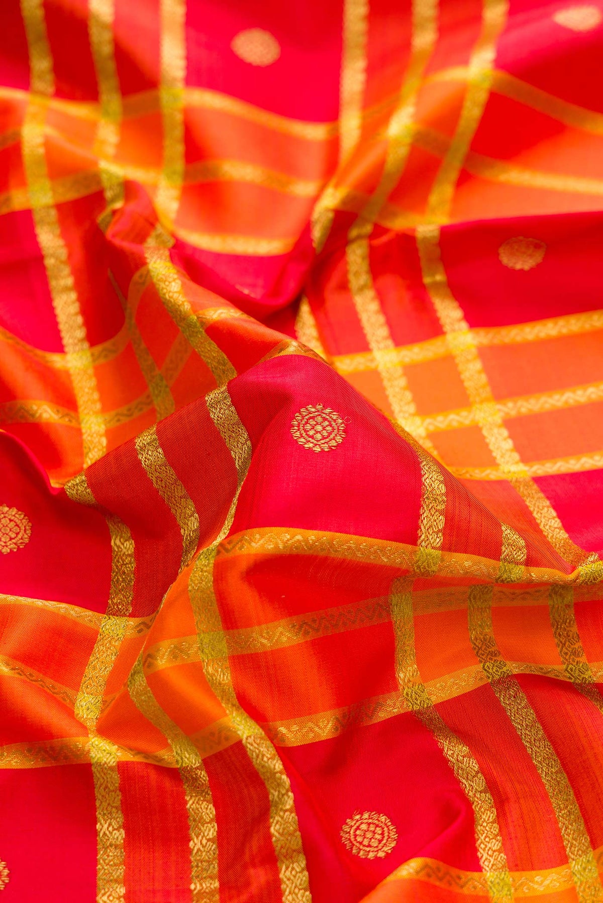 Close up of Pure Silk Pure Zari Orange Dual Tone Kanchipuram Saree with Checked design on the body and Zari Border displaying folds