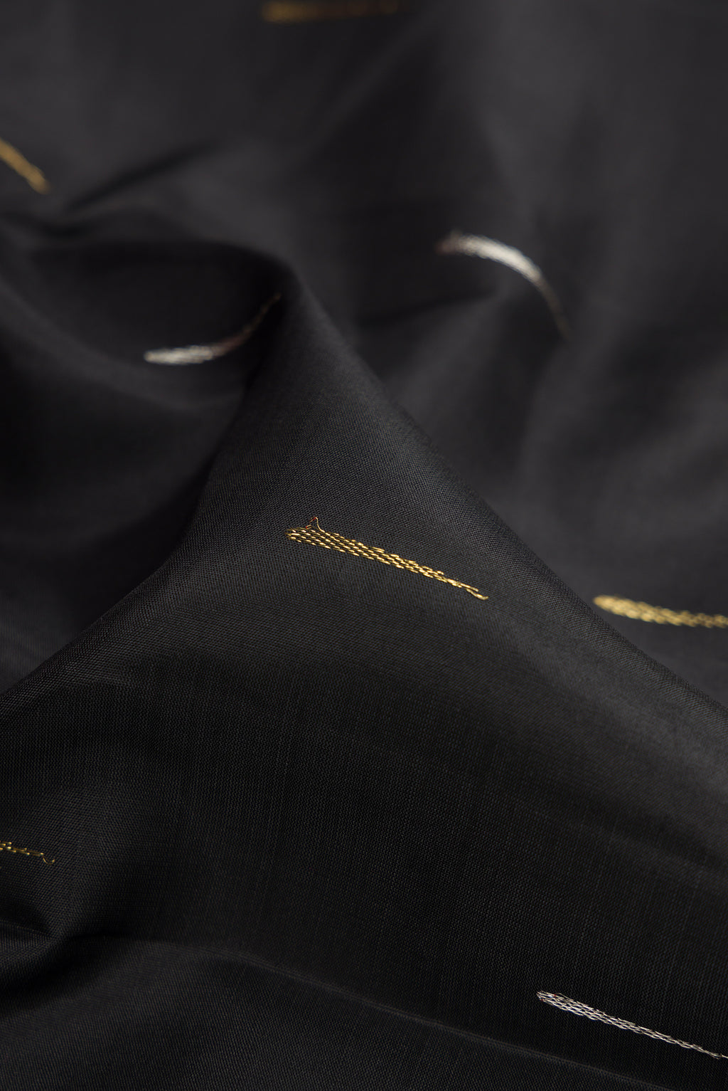 Close up of Black Kanjivaram Silk Saree with Zari Butta on the body and Zari Border.  displaying folds