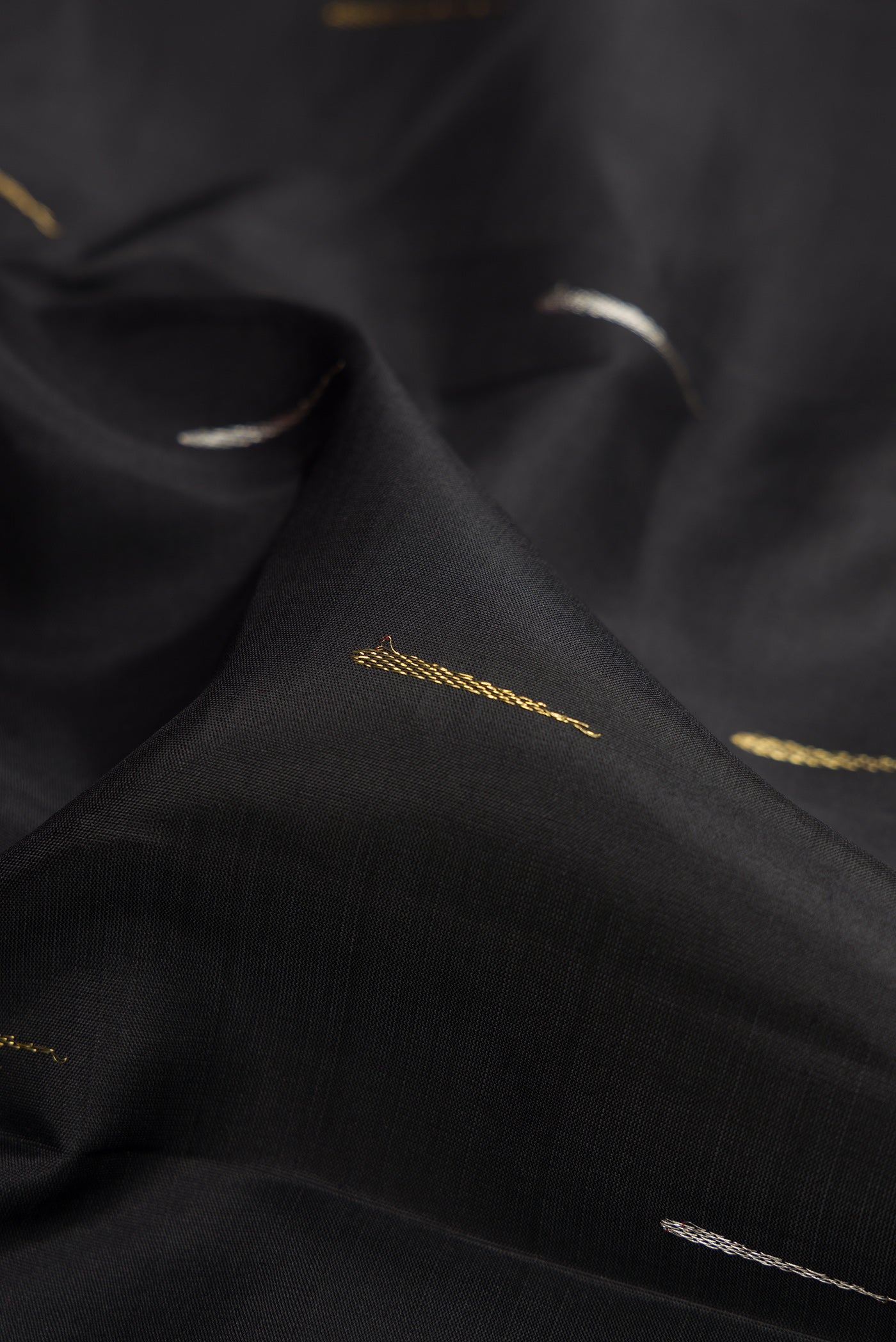 Close up of Black Kanjivaram Silk Saree with Zari Butta on the body and Zari Border.  displaying folds