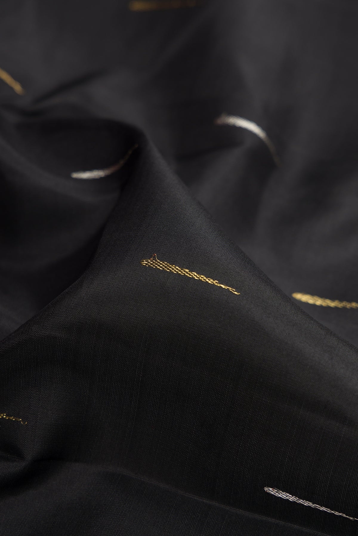 Close up of Black Kanjivaram Silk Saree with Zari Butta on the body and Zari Border.  displaying folds