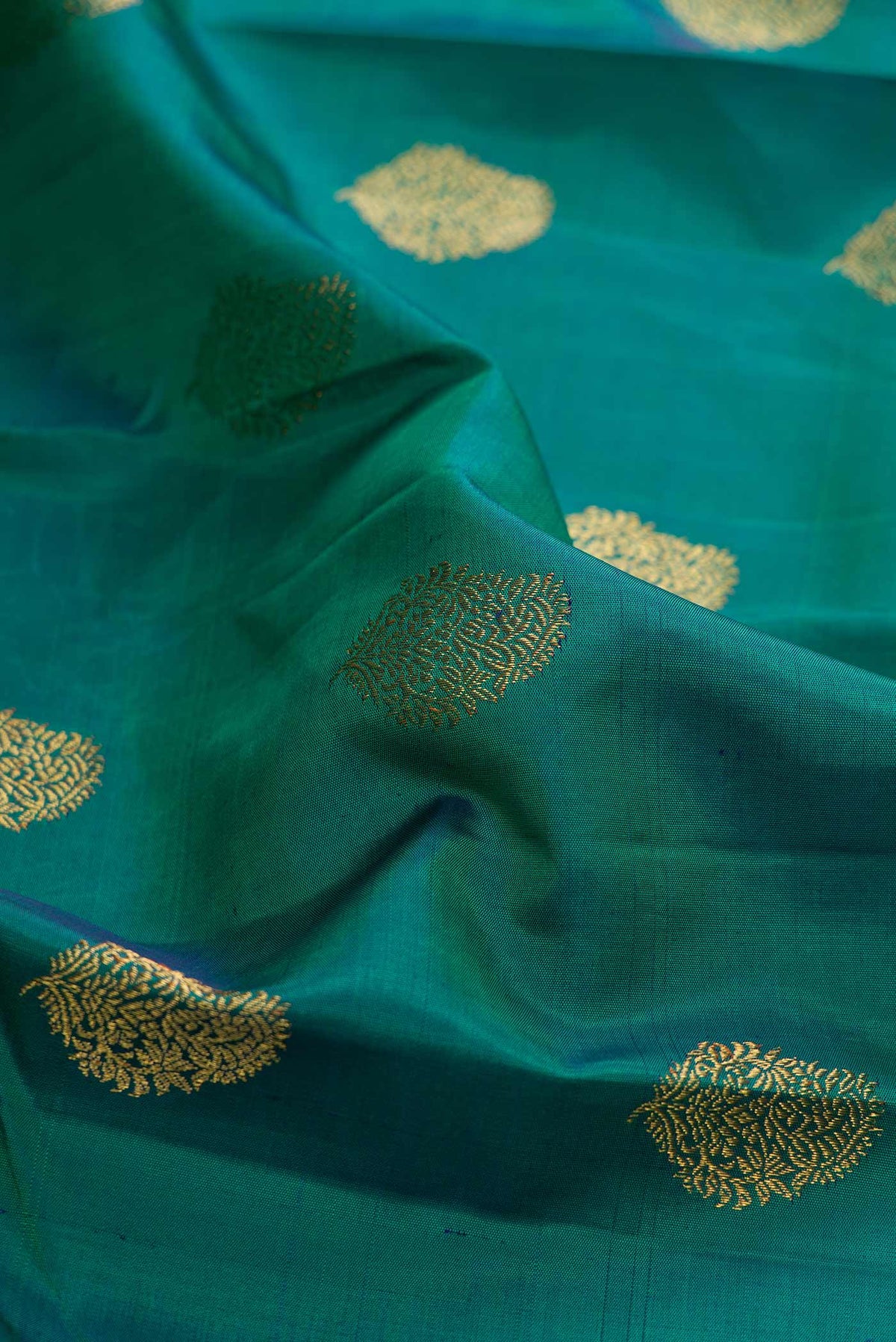 Close up of Pure Silk Pure Zari Green Dual Tone Kanchipuram Saree with Zari Butta on the body and Zari Border displaying folds