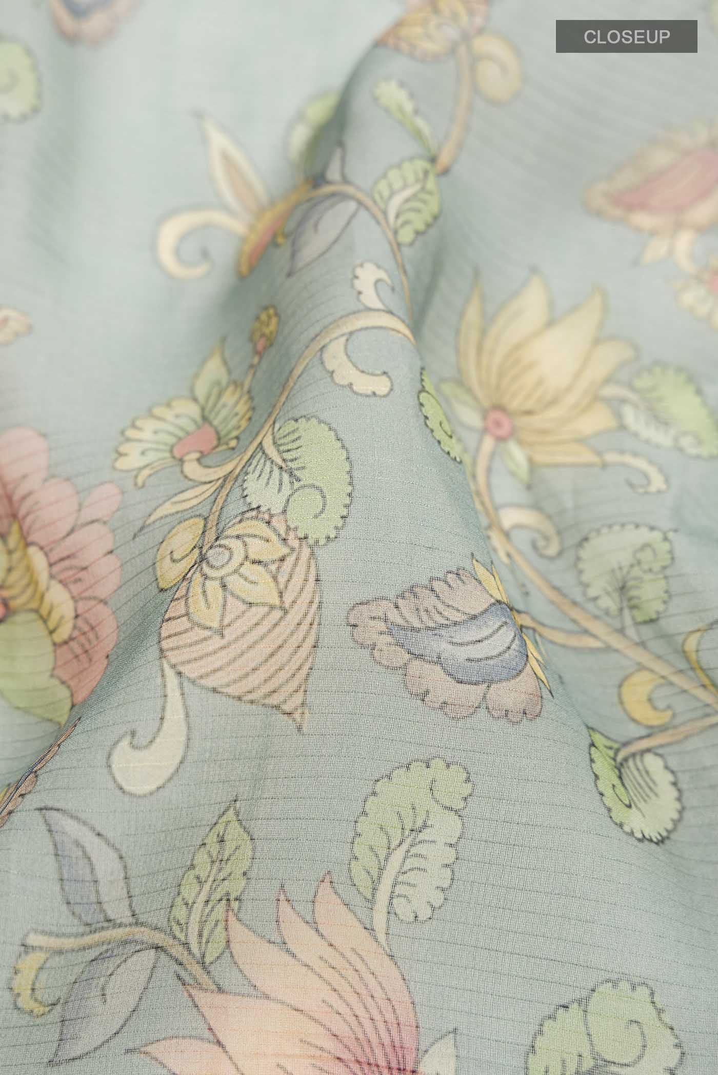 Close up of Green Organza Silk Saree Printed design on the body and Embroidery Border displaying folds