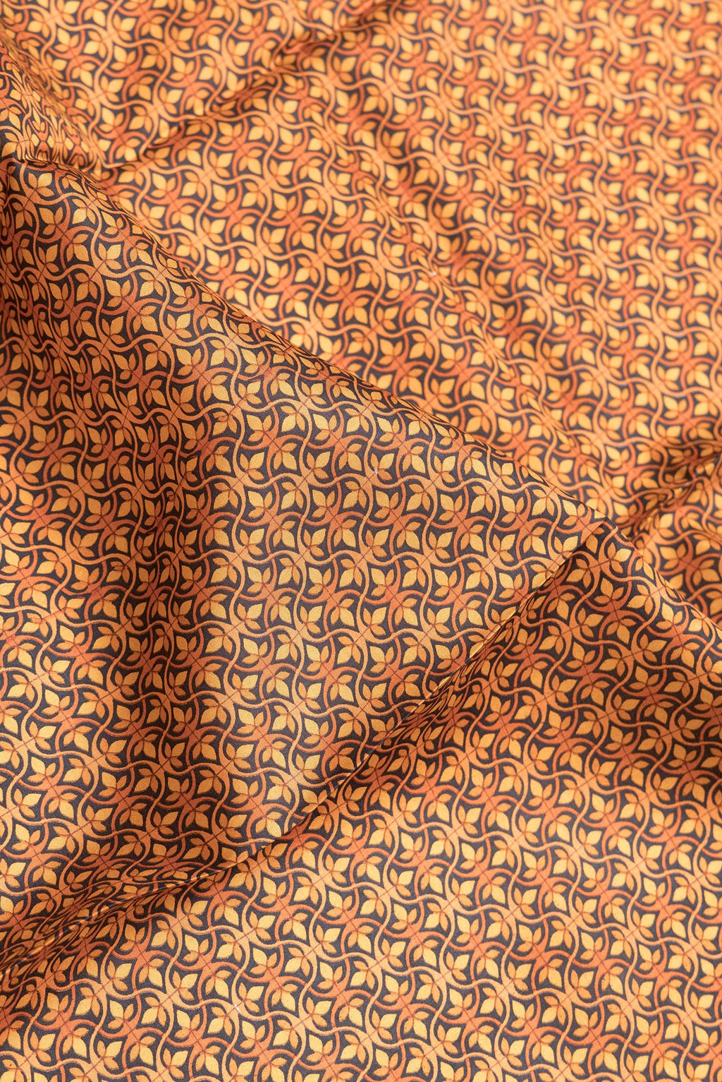 Close up of Orange Dual Tone Printed Silk Saree with Printed design on the body and Printed Border.  displaying folds