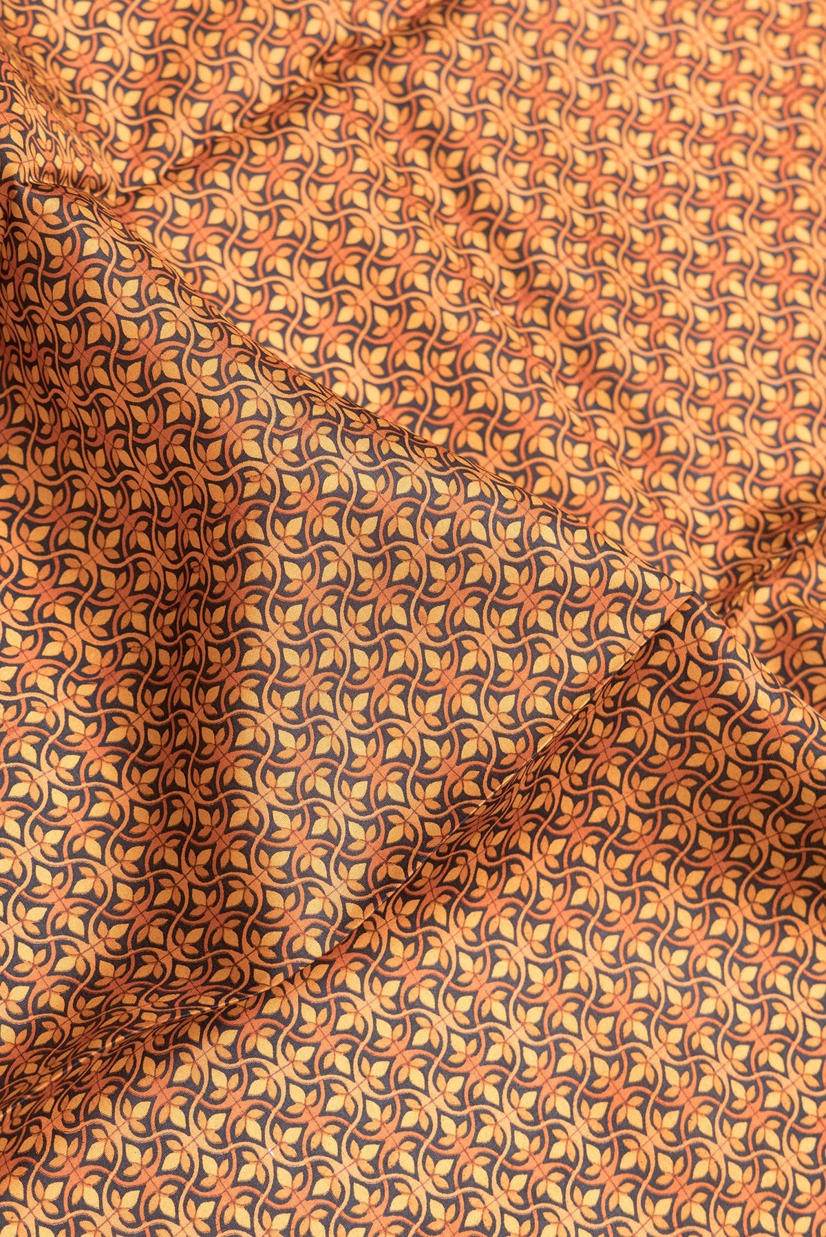 Close up of Orange Dual Tone Printed Silk Saree with Printed design on the body and Printed Border.  displaying folds