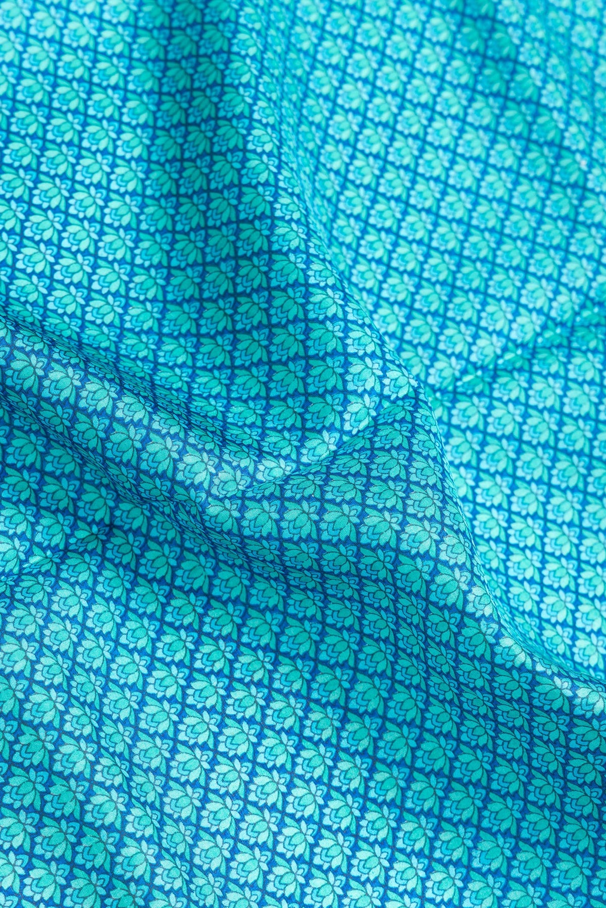 Close up of Peacock Blue Dual Tone Printed Silk Saree with Printed design on the body and Printed Border.  displaying folds