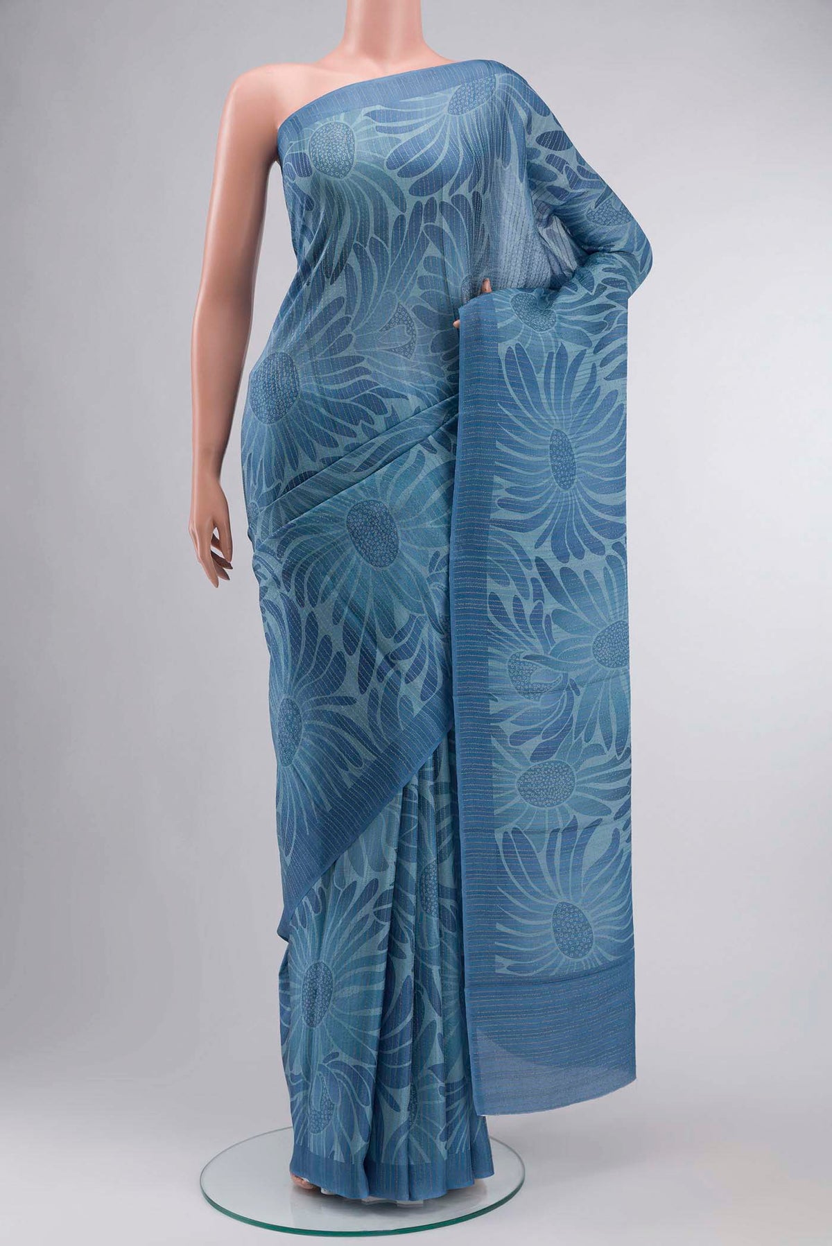 Blue Crepe Saree Printed design on the body and Zari Border displayed on a mannequin