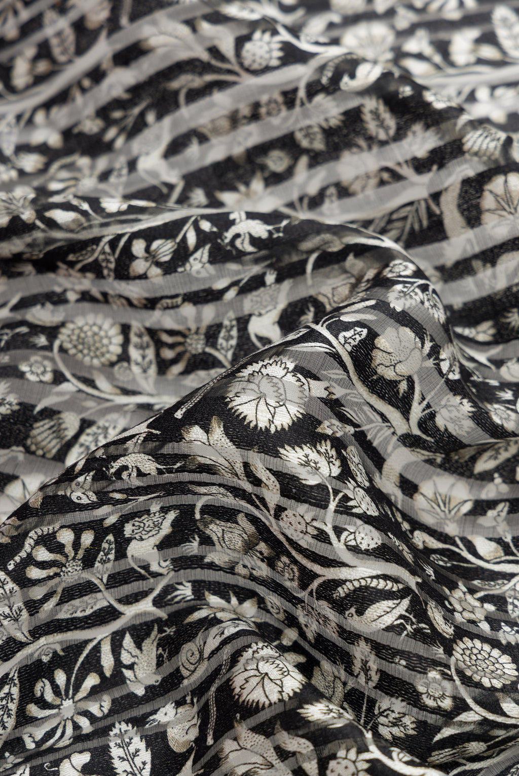 Close up of Black Dual Tone Tussar Silk Saree with Printed design on the body and Zari Border.  displaying folds