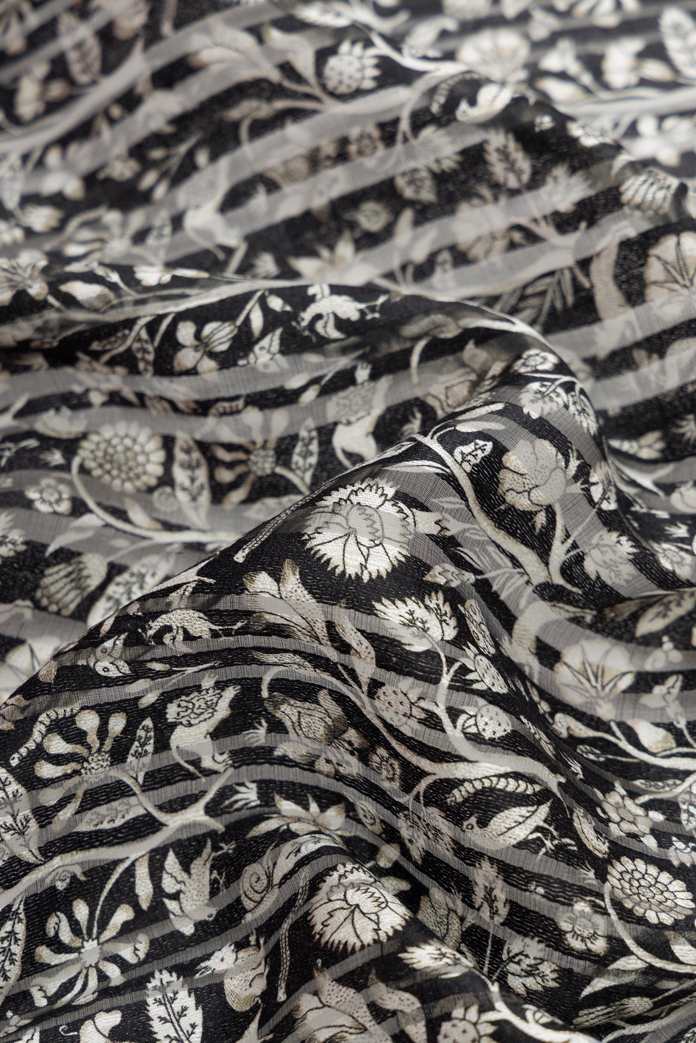 Close up of Black Dual Tone Tussar Silk Saree with Printed design on the body and Zari Border.  displaying folds