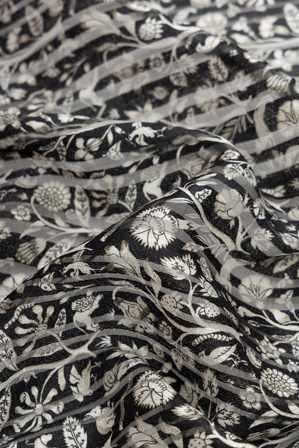 Close up of Black Dual Tone Tussar Silk Saree with Printed design on the body and Zari Border.  displaying folds