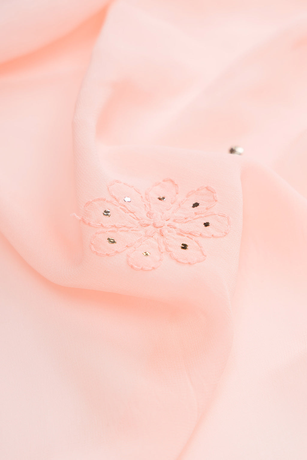 Close up of Peach Dual Tone Georgette Saree with Embroidery on the body and Embroidery Border.  displaying folds