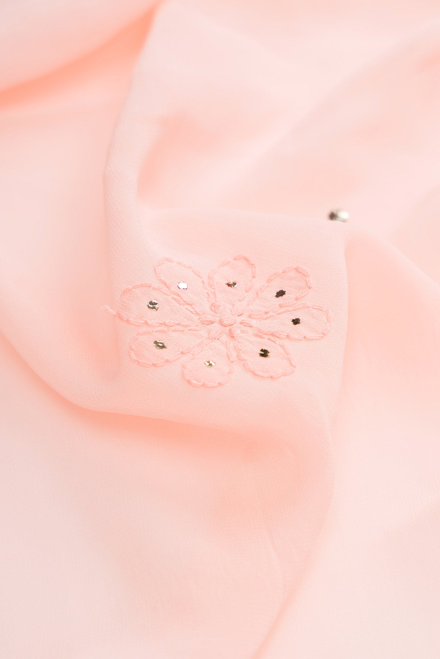 Close up of Peach Dual Tone Georgette Saree with Embroidery on the body and Embroidery Border.  displaying folds