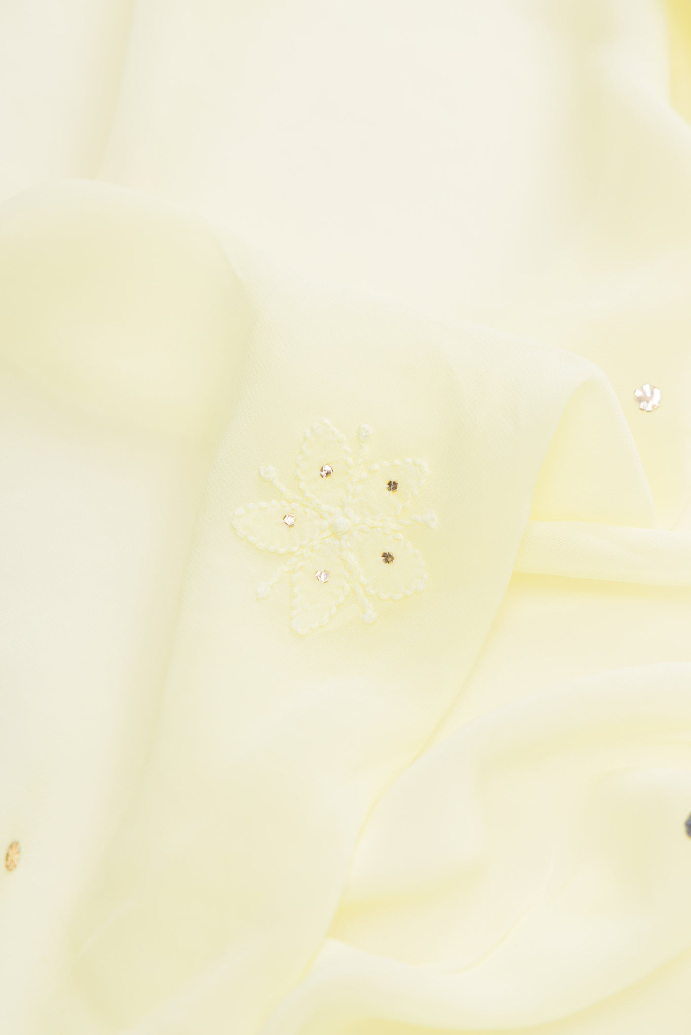 Close up of Lemon Yellow Dual Tone Georgette Saree with Embroidery on the body and Embroidery Border.  displaying folds