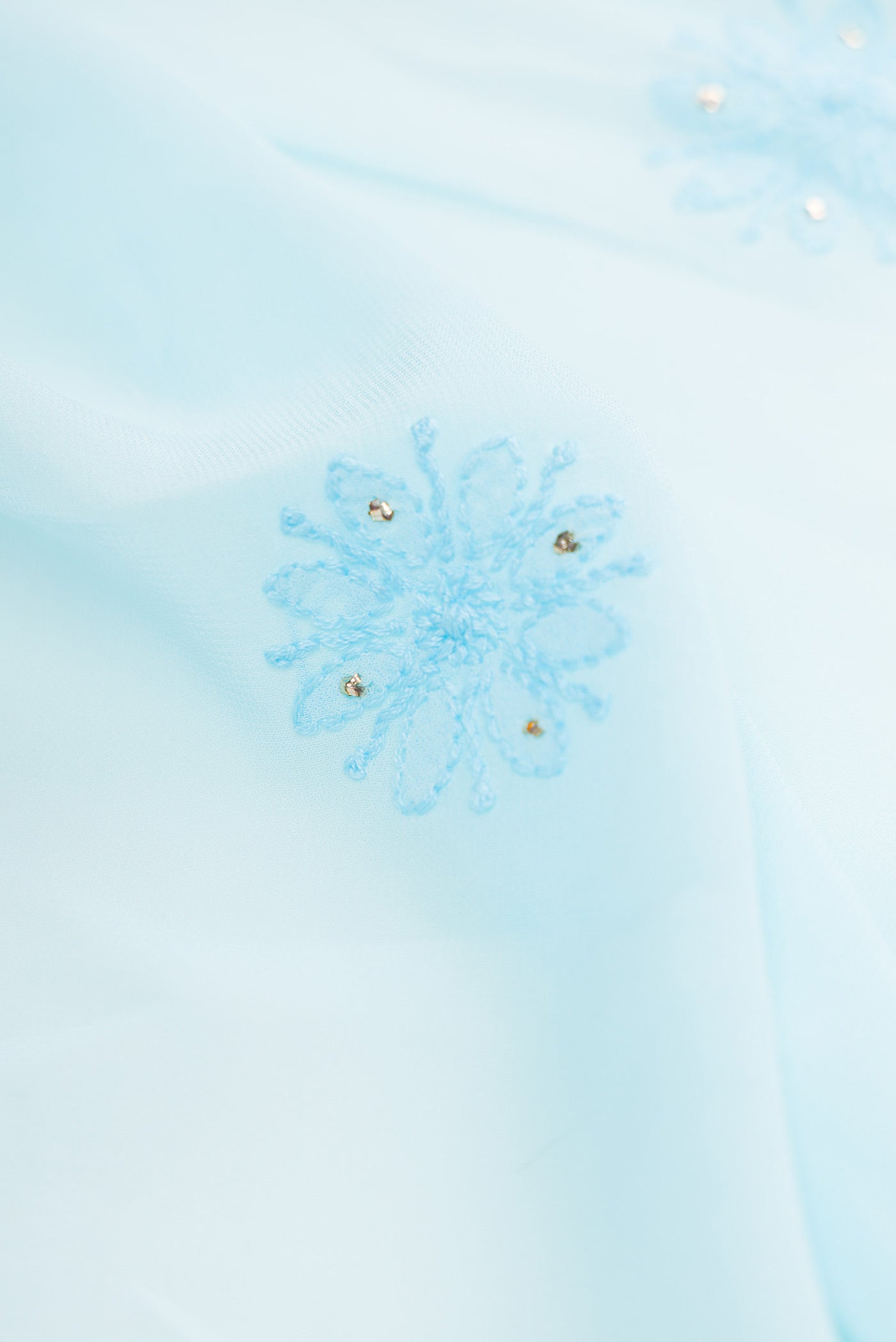 Close up of Sky Blue Dual Tone Georgette Saree with Embroidery on the body and Embroidery Border.  displaying folds