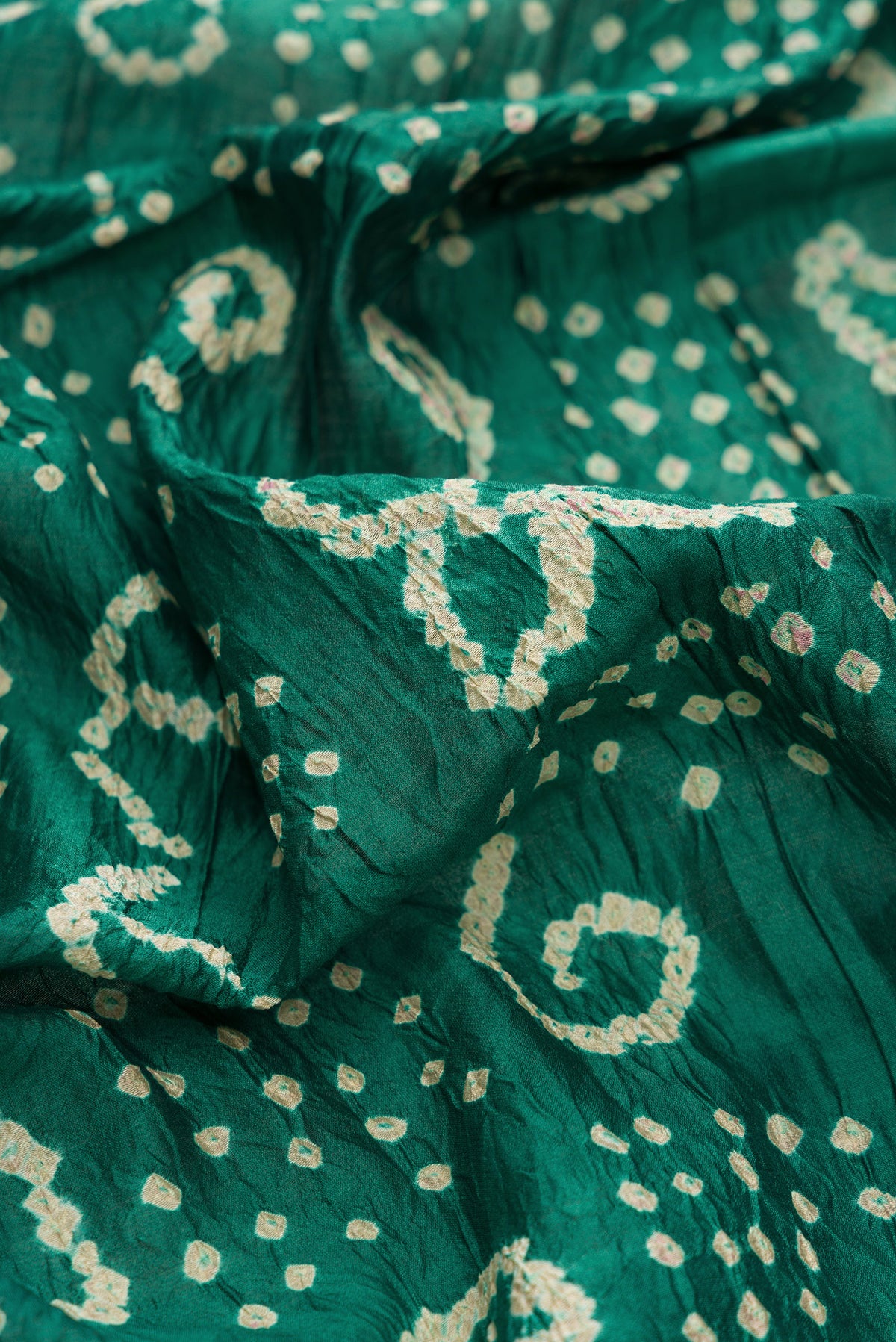 Close up of Green Dual Tone Bandhani Silk Saree with Bandhani Print on the body and Zari Border.  displaying folds