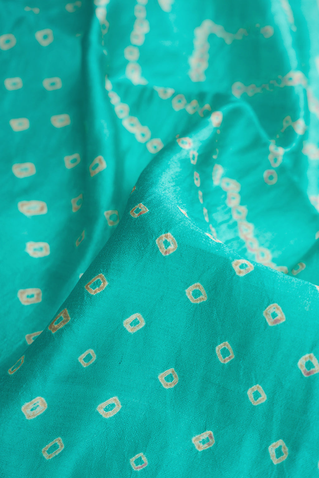Close up of Sky Blue Dual Tone Bandhani Silk Saree with Bandhani Print on the body and Zari Border.  displaying folds
