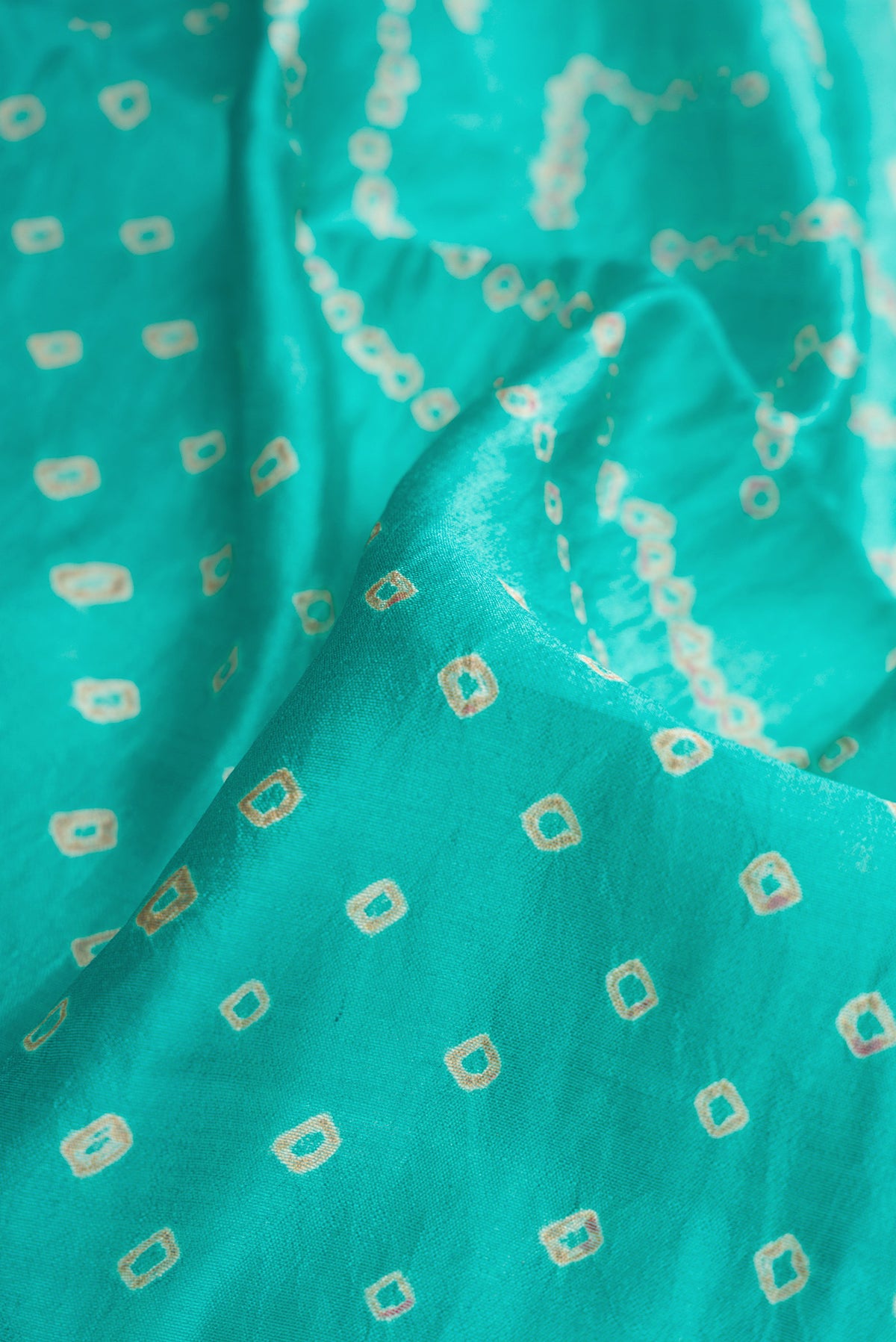 Close up of Sky Blue Dual Tone Bandhani Silk Saree with Bandhani Print on the body and Zari Border.  displaying folds