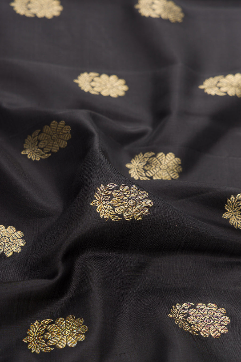 Close up of Black Dual Tone Kanjivaram Silk Saree with Zari Butta on the body and Zari Border.  displaying folds