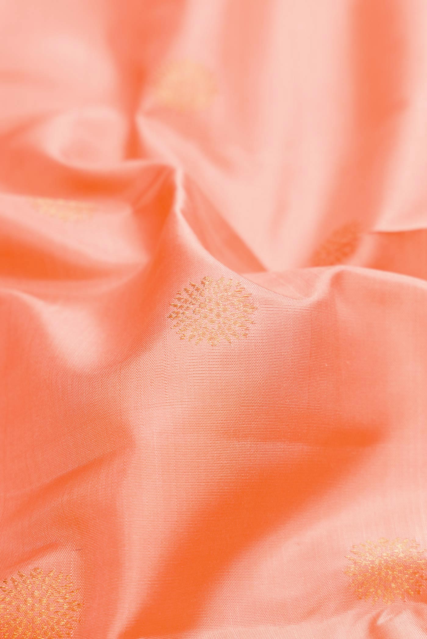 Close up of Peach Dual Tone Kanchipuram Silk Saree with Zari Butta on the body and Zari Border.  displaying folds
