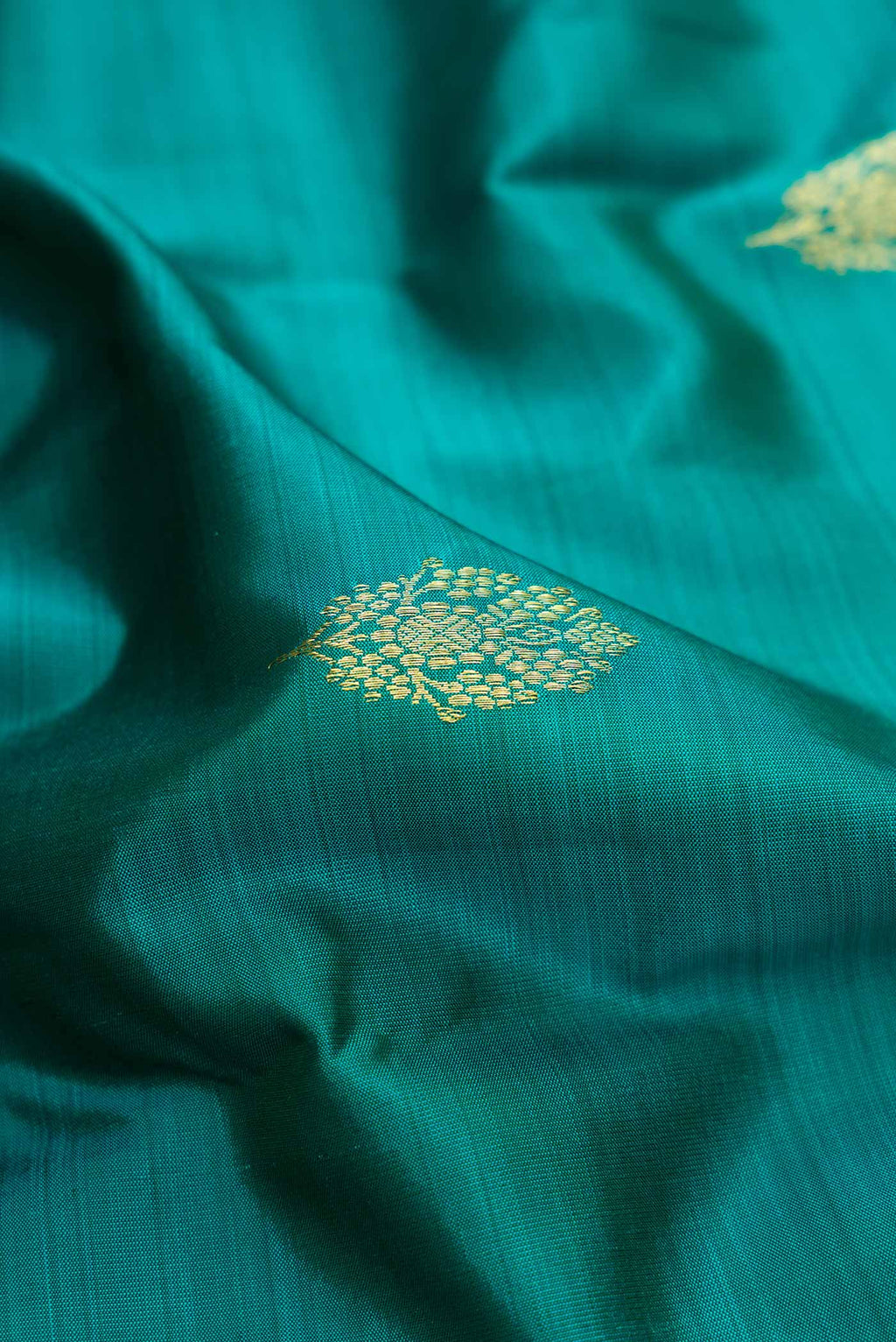 Close up of Peacock Blue Dual Tone Kanchipuram Silk Saree with Zari Butta on the body and Zari Border.  displaying folds