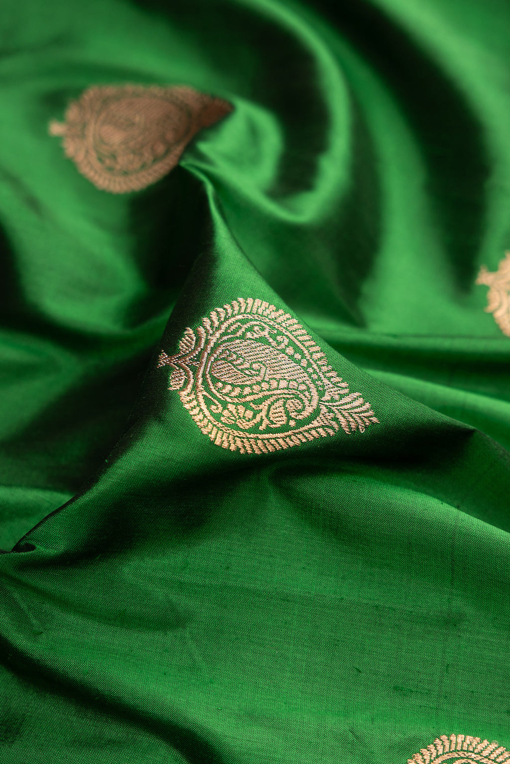 Close up of Green Dual Tone Banarasi Silk Saree with Zari Butta on the body and Zari Border.  displaying folds