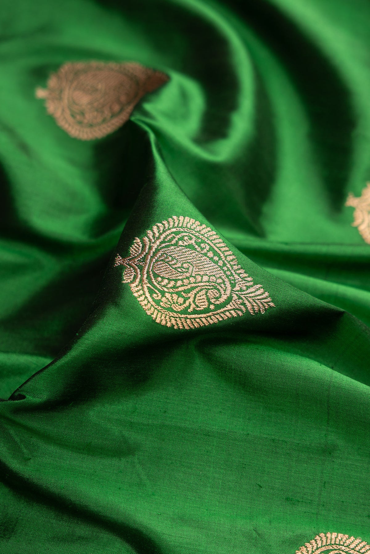 Close up of Green Dual Tone Banarasi Silk Saree with Zari Butta on the body and Zari Border.  displaying folds