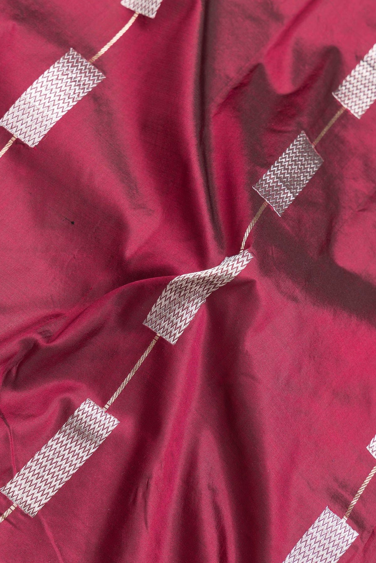 Close up of Maroon Dual Tone Banarasi Silk Saree with Zari Butta on the body and Zari Border.  displaying folds