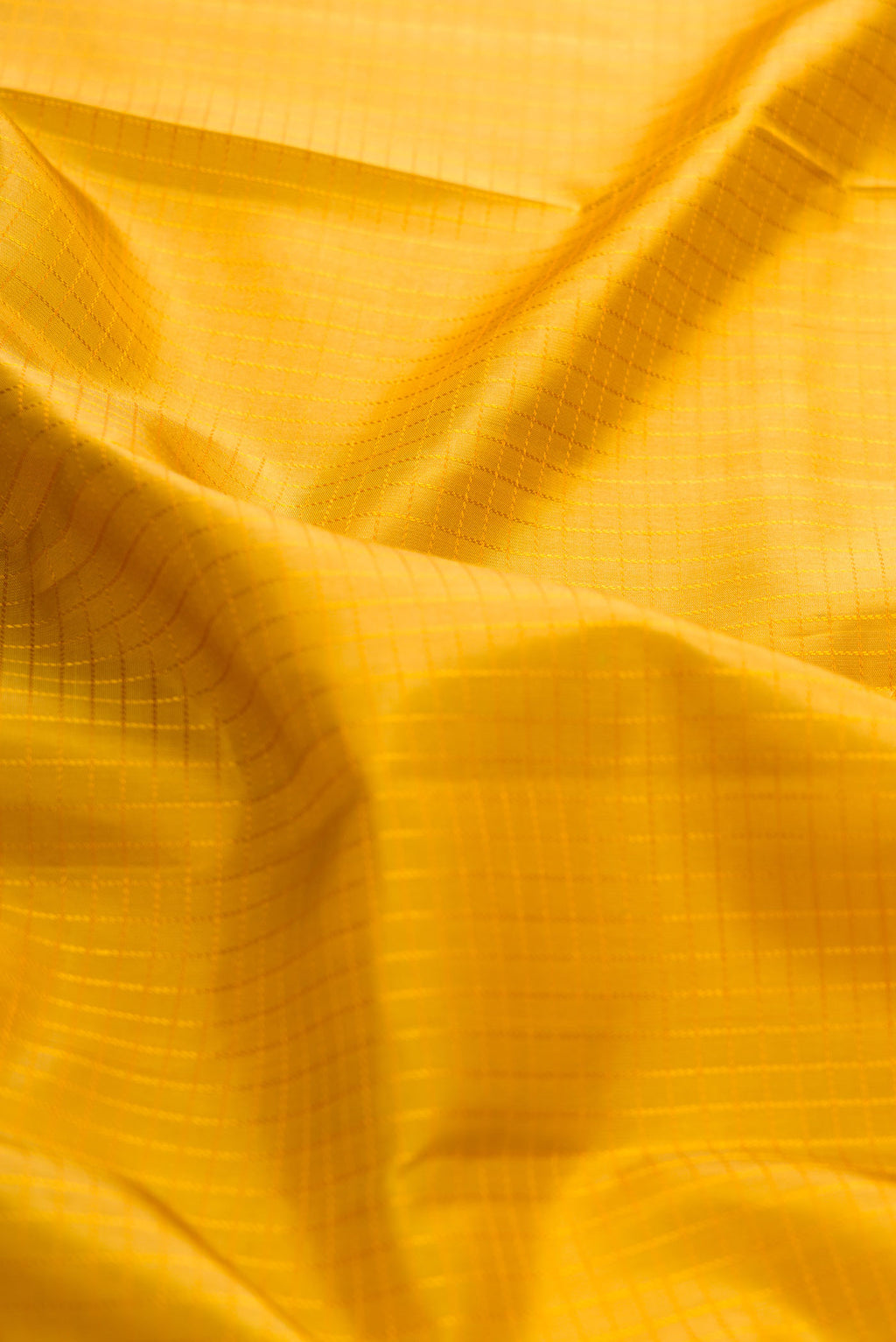 Close up of Mustard Dual Tone Kanchipuram Silk Saree with Zari Butta on the body and Zari Border displaying folds