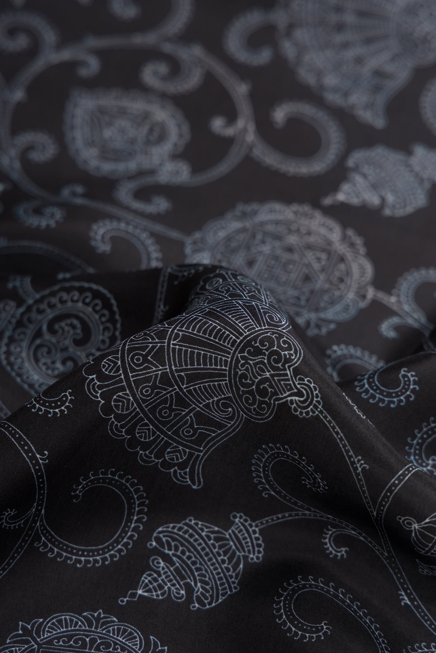 Close up of Black Dual Tone Printed Silk Saree with Printed design on the body and Plain Border.  displaying folds