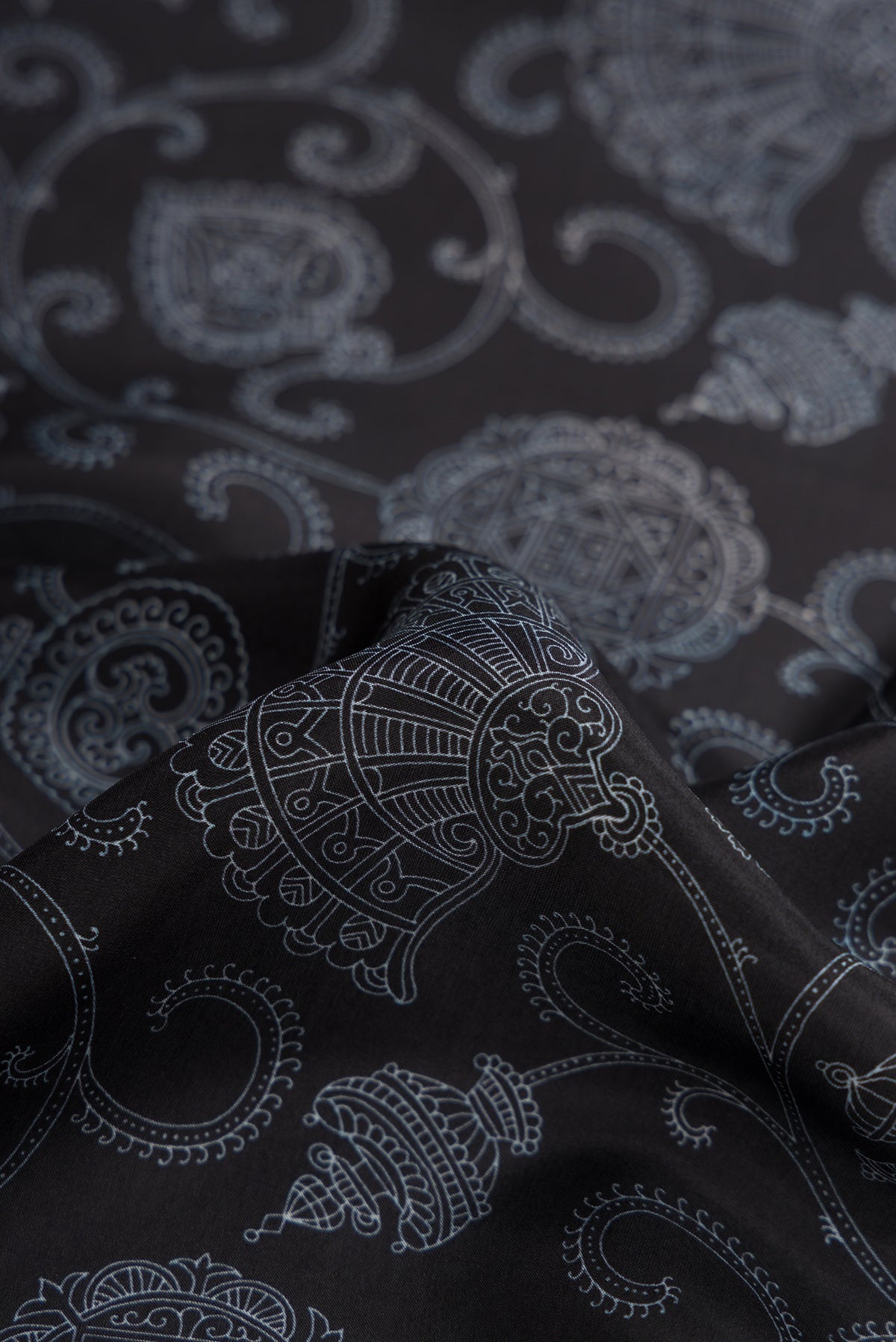 Close up of Black Dual Tone Printed Silk Saree with Printed design on the body and Plain Border.  displaying folds