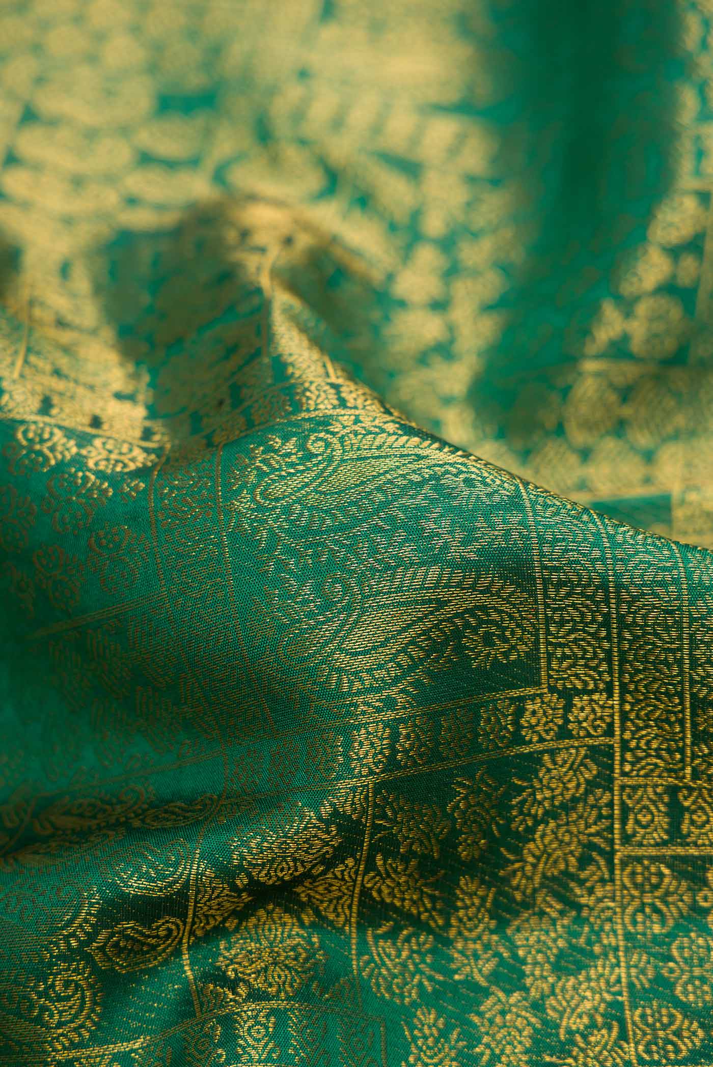 Close up of Green Dual Tone Kanchipuram Silk Saree with Zari Brocade on the body and Zari Border.  displaying folds