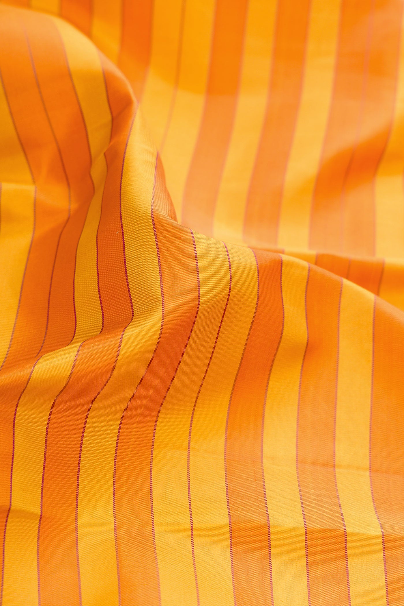 Close up of Mustard and Orange Color Kanjivaram Silk Saree with Stripes on the body and Zari Border.  displaying folds