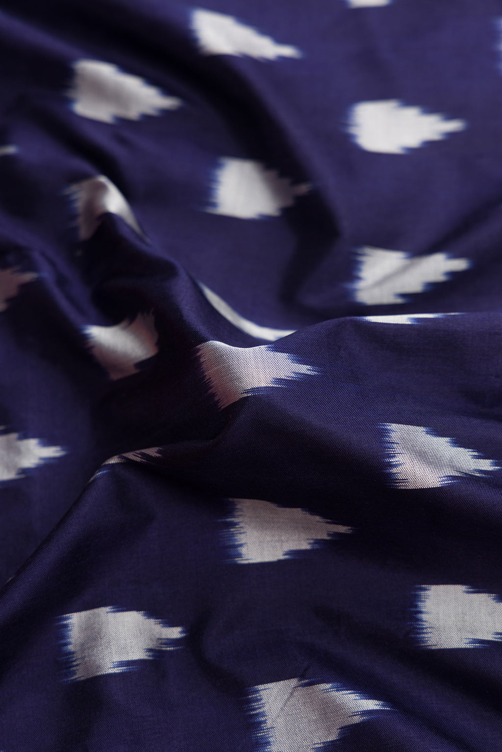 Close up of Navy Blue Dual Tone Double Ikat Saree with Ikat Print on the body and Zari Border.  displaying folds
