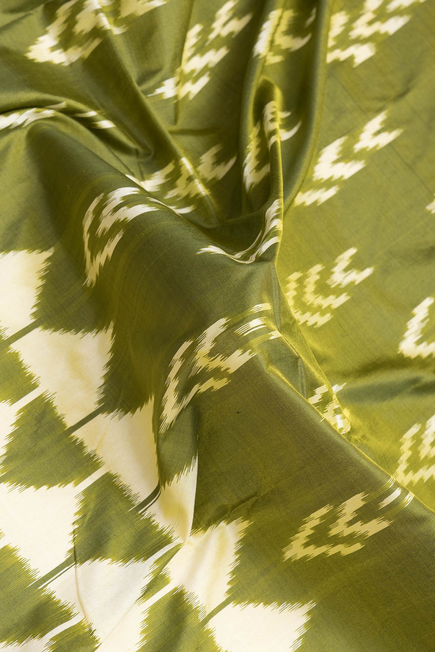 Close up of Mehandi Green Dual Tone Double Ikat Saree with Ikat Print on the body and Ikat Border.  displaying folds