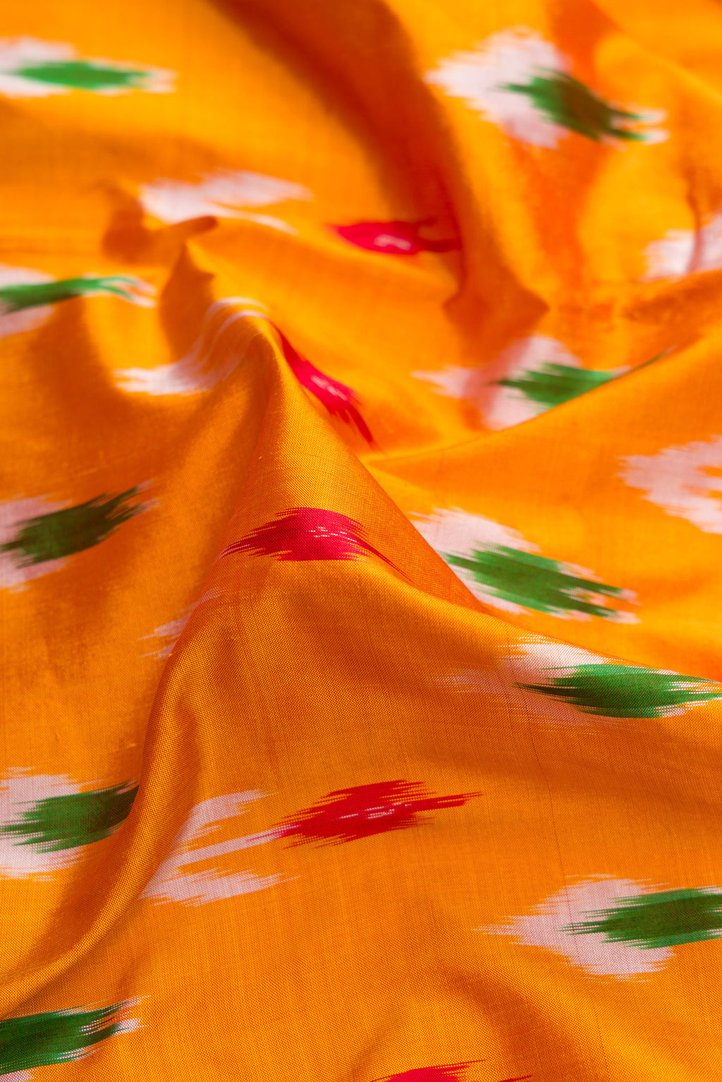 Close up of Mustard Dual Tone Double Ikat Saree with Ikat Print on the body and Zari Border.  displaying folds