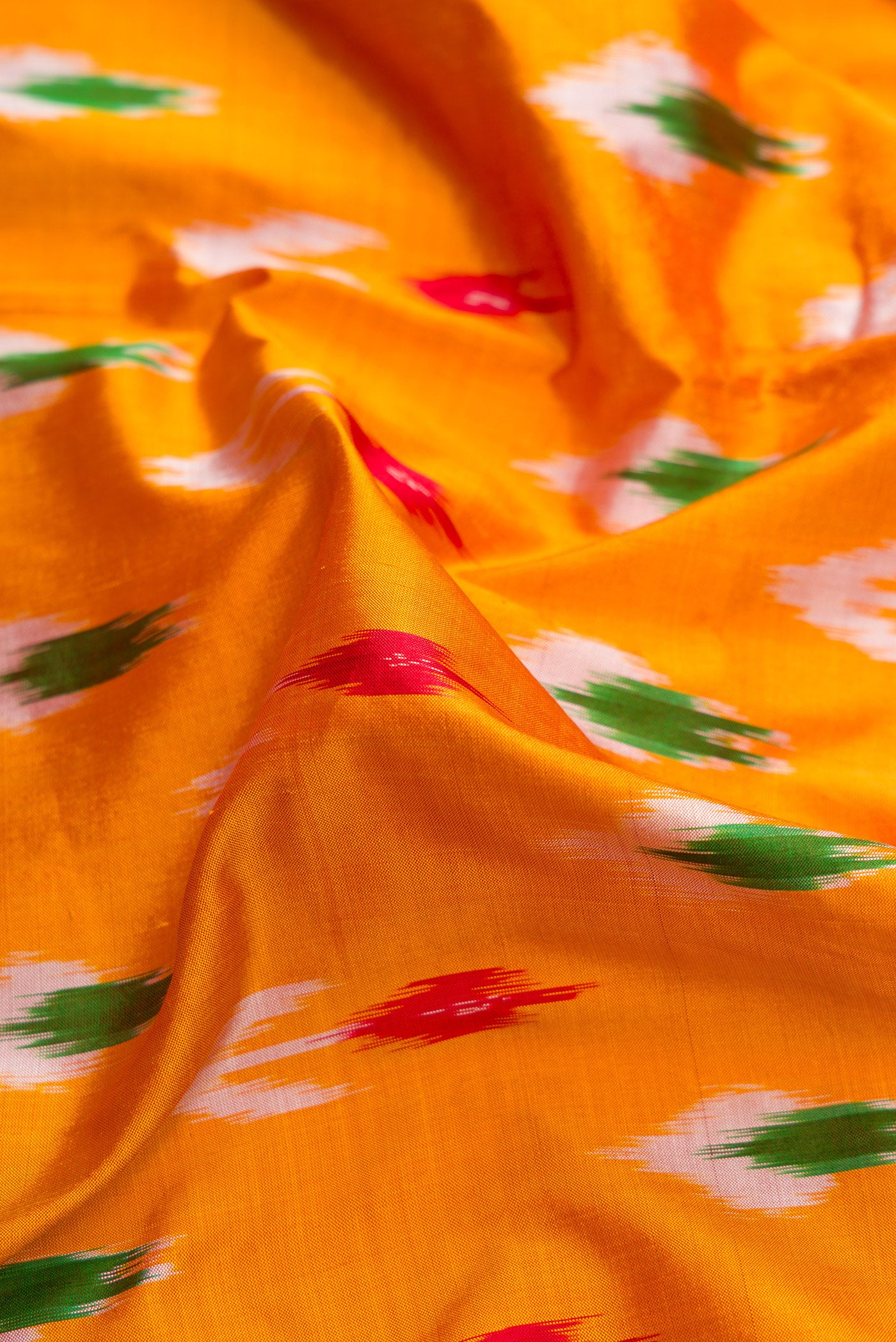Close up of Mustard Dual Tone Double Ikat Saree with Ikat Print on the body and Zari Border.  displaying folds