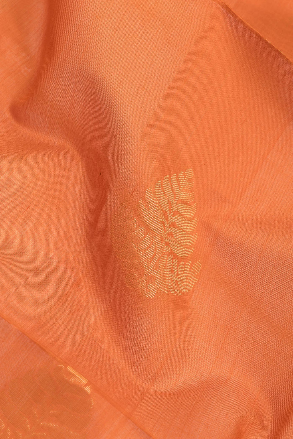 Close up of Orange Silk Cotton Saree with Zari Butta on the body and Zari Border.  displaying folds