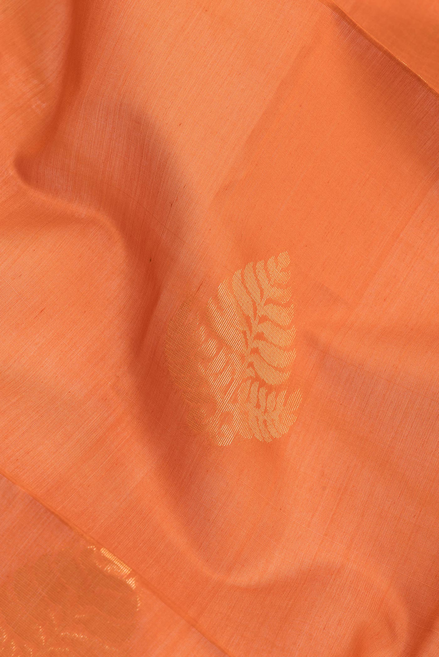 Close up of Orange Silk Cotton Saree with Zari Butta on the body and Zari Border.  displaying folds