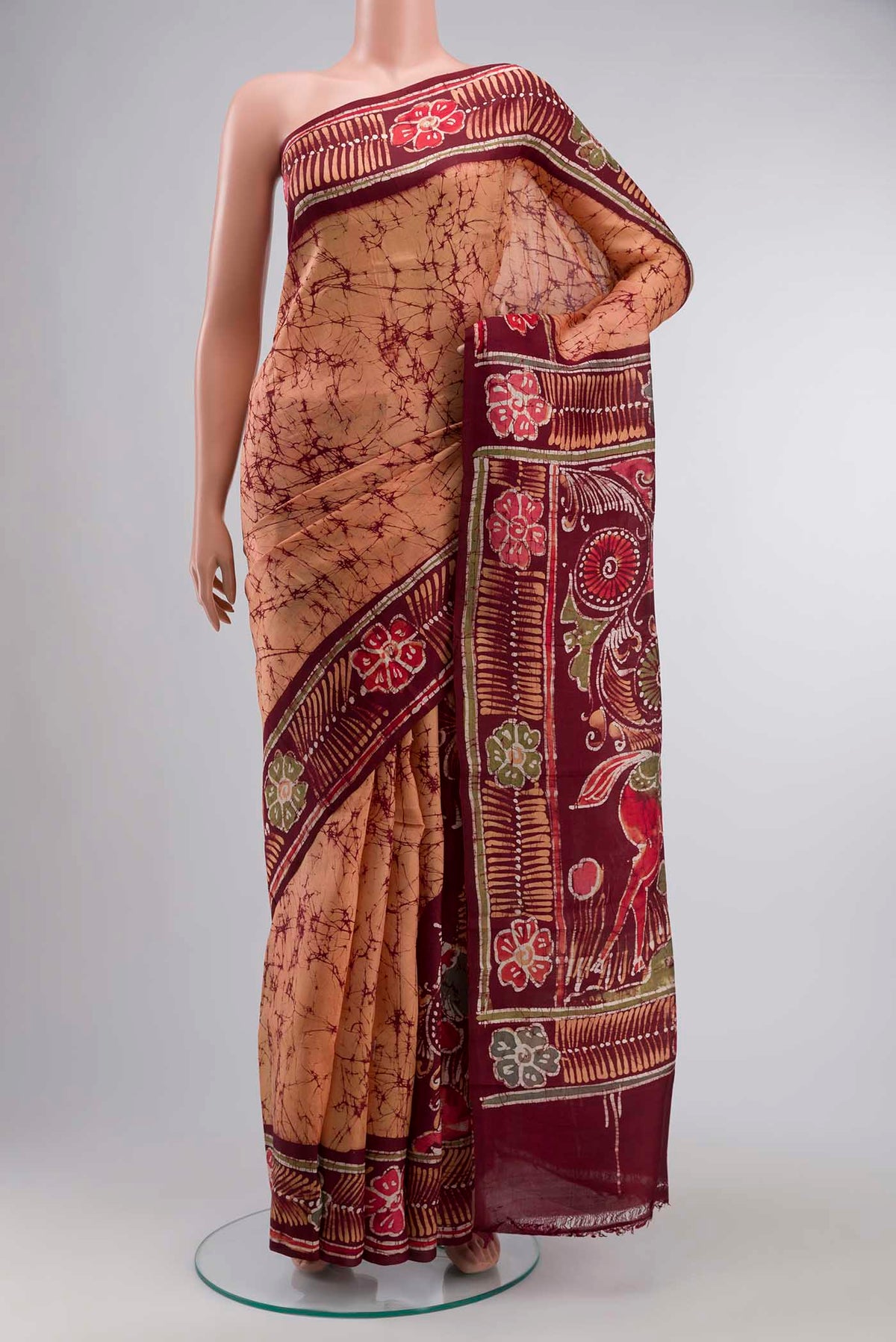Orange Printed Silk Saree with Batik Print on the body and Printed Border displayed on a mannequin