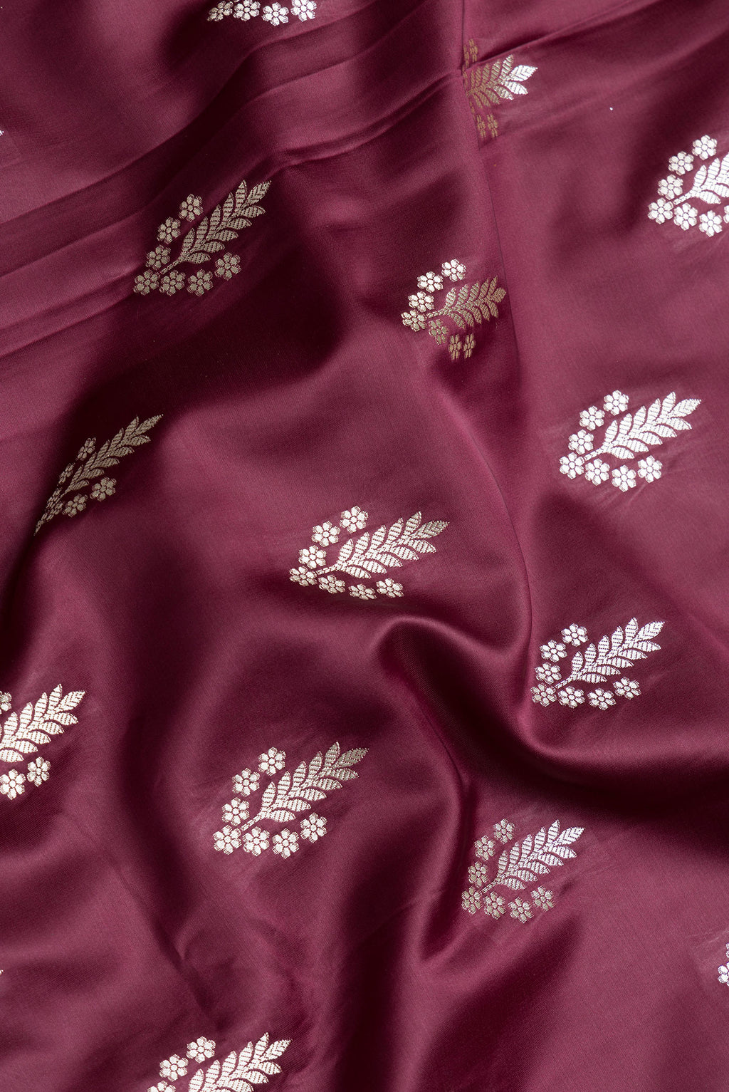 Close up of Maroon Dual Tone Banarasi Silk Saree with Zari Butta on the body and Zari Border.  displaying folds